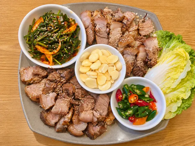 돼지수육보쌈 한 상. 도톰한 수육과 부추무침, 마늘, 고추, 배추